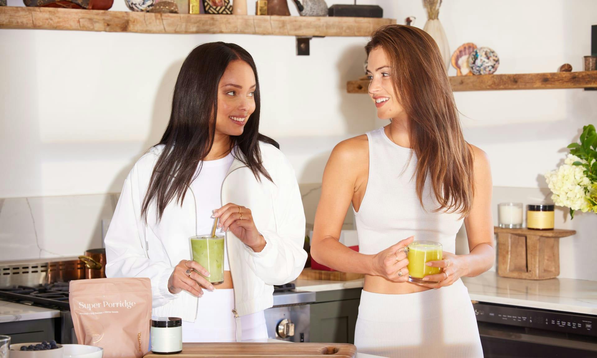 Two women holding glasses of Kroma Majik Matcha and Ultimate Vitality Latte.