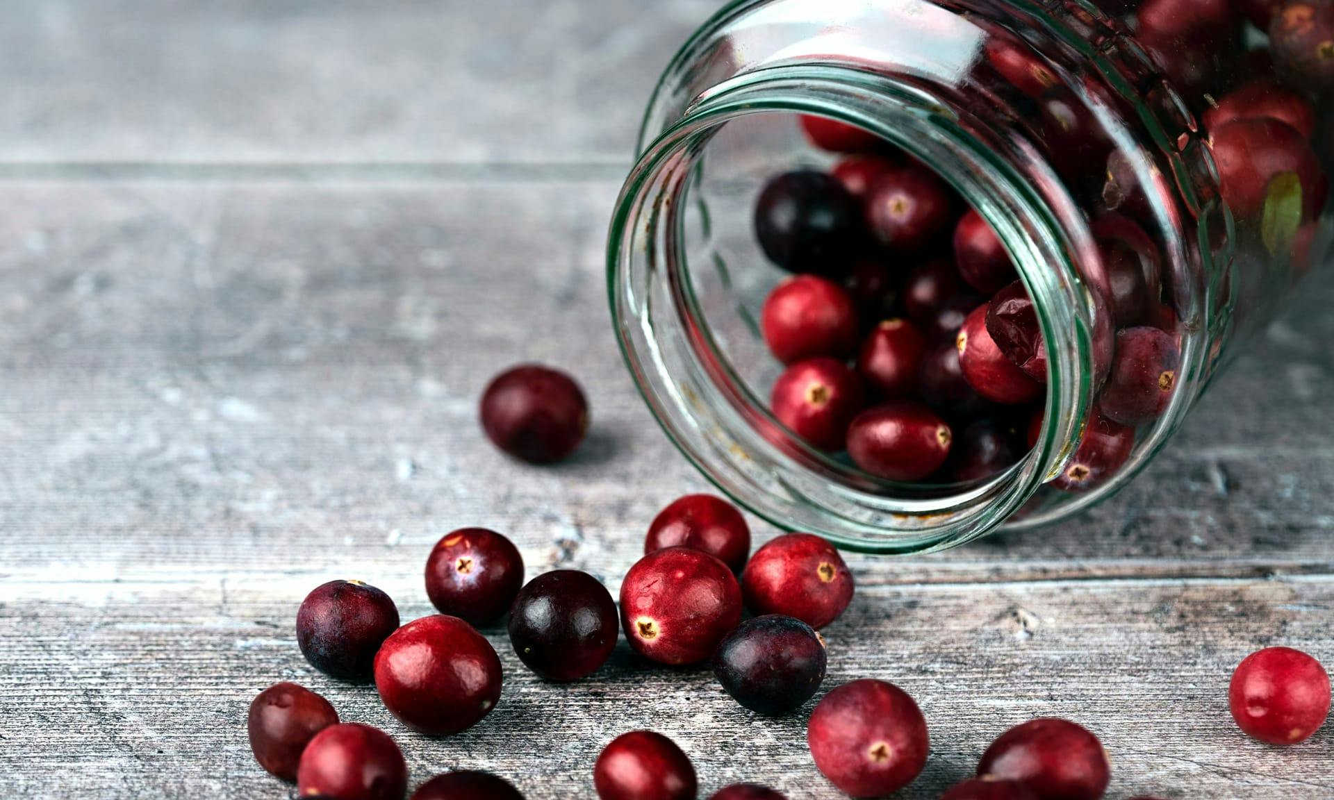 Cranberries spilling out of a tipped-over jar.