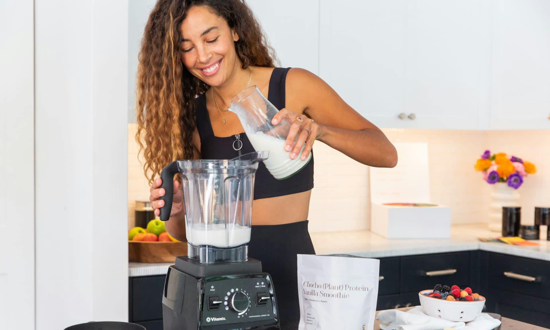 A woman preparing a dairy-free Kroma Vanilla Cinnamon Plant Protein Smoothie in a blender.